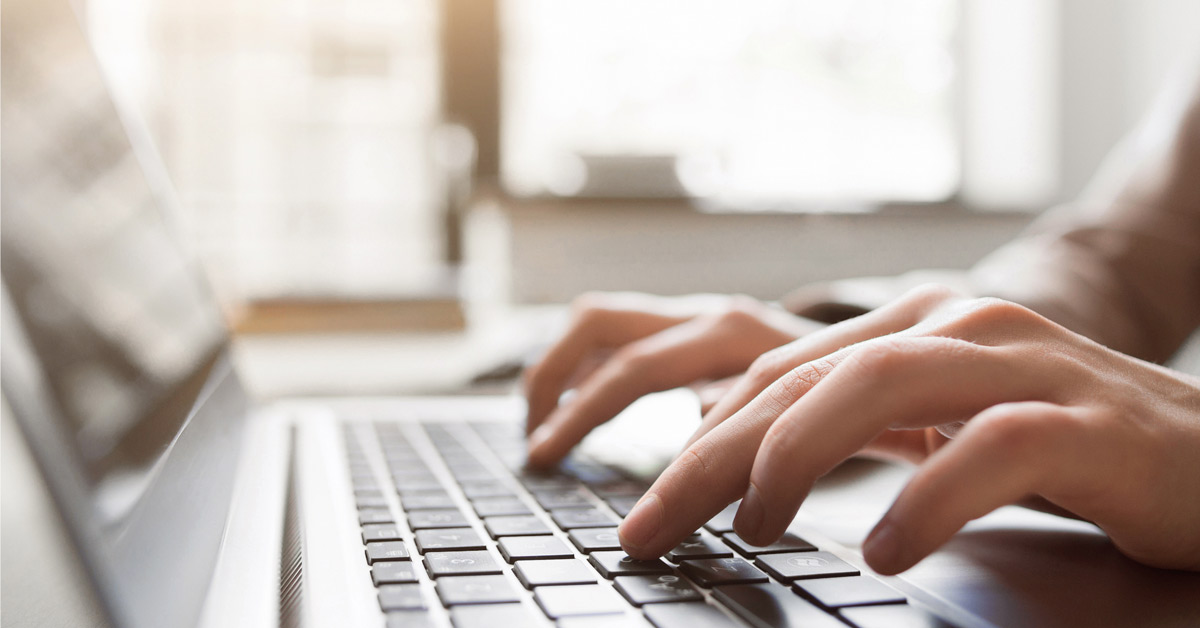 Hands typing on a laptop computer