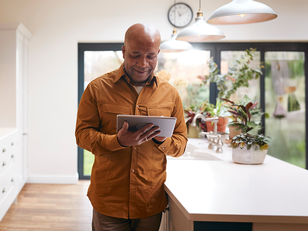 man using ipad in kitchen to access his insurance documents