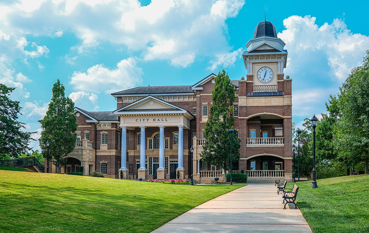 town hall in a beautiful park with green grass and a paved sidewalk leading to the building