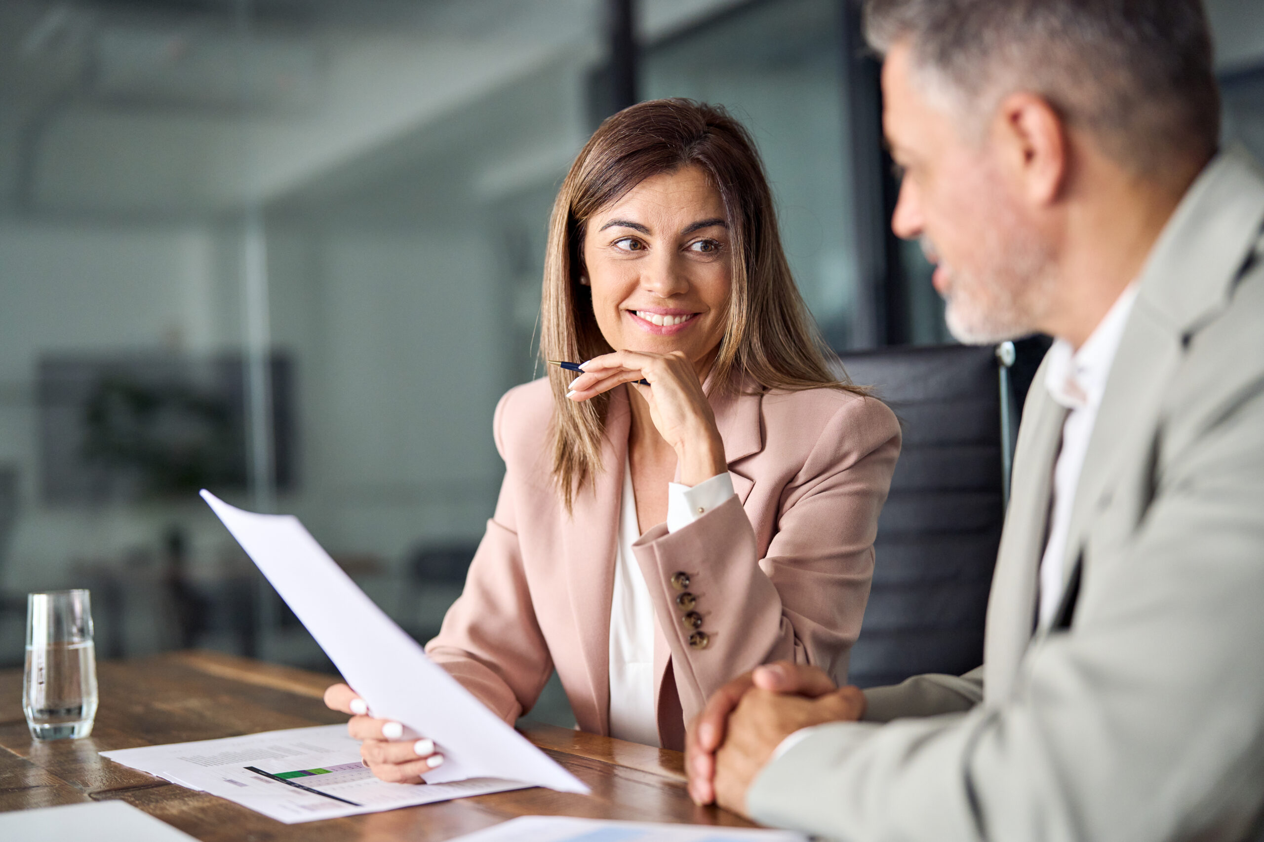 Two business executives discussing financial legal papers in office at meeting.